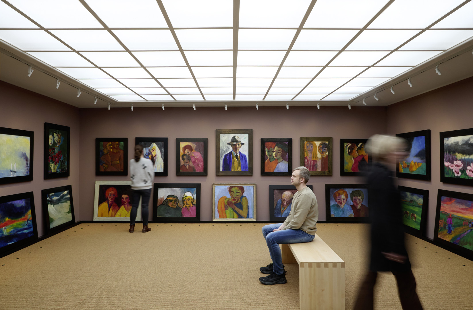 Drei Besucher betrachten Gemälde von Emil Nolde im Bildersaal des Nolde-Hauses.