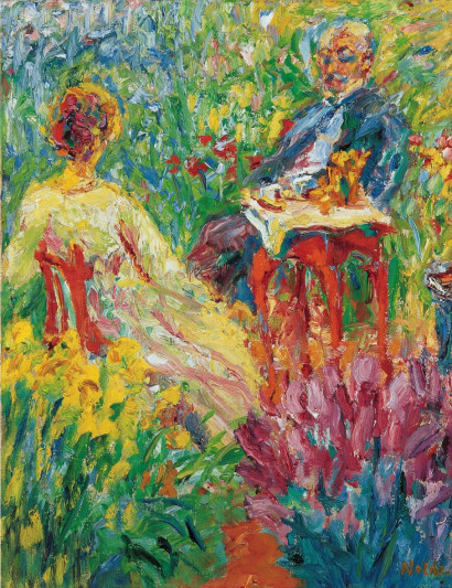 Mann und Frau sitzen bei sonnigem Wetter an einem kleinen gedeckten Tisch in einem bl&uuml;henden Garten, die Frau von hinten, der Mann von vorne zu sehen.