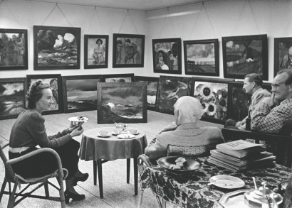 Emil Nolde mit Jolanthe, Joachim von Lepel und Carl Hagens sitzend im Bildersaal Seeb&uuml;ll, umgeben von Nolde-Gem&auml;lden.