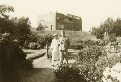 Ada und Emil Nolde gehen eingehakt durch den Nolde-Garten, im Hintergrund das Nolde-Haus, 1940.