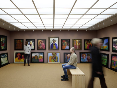 View of the Picture Hall in the Nolde House with densely hung works by Emil Nolde, and visitors in motion.