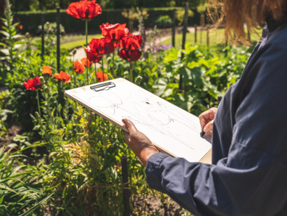 Person im Nolde-Garten mit Zeichenbrett, auf dem eine Skizze entsteht.