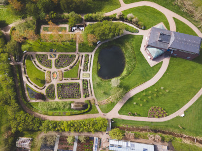 Vogelperspektive auf das Nolde-Haus und den Nolde-Garten im fr&uuml;hen Fr&uuml;hling; die Beete sind noch kahl, geschwungene Wege sind gut sichtbar.